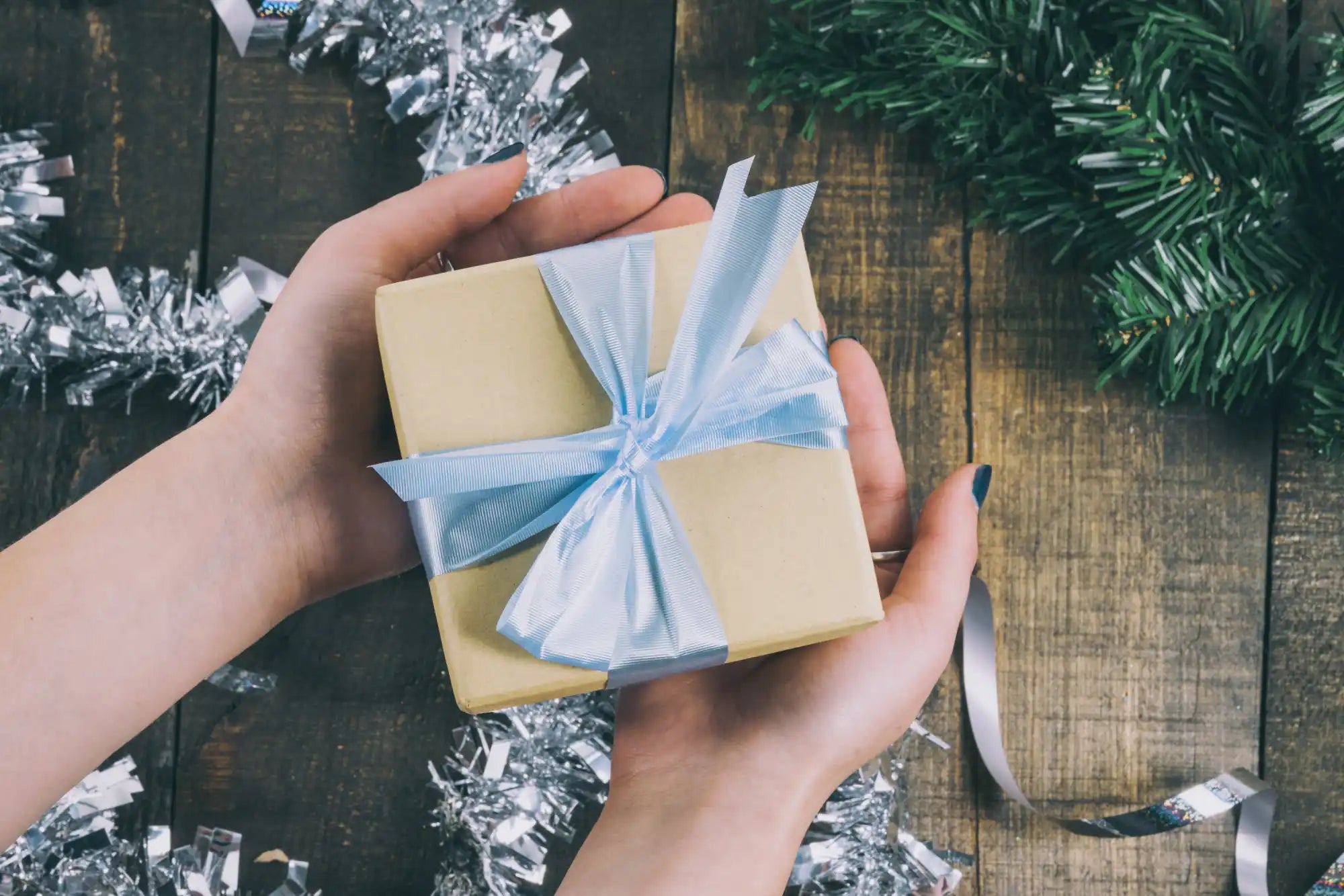 A small, light brown gift box tied with a light blue ribbon.